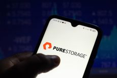 Pure Storage logo on a smartphone held in someone's hand, set against a dark blue background