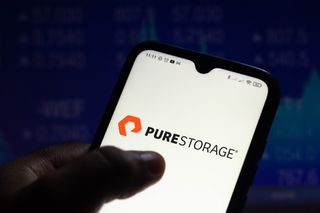 Pure Storage logo on a smartphone held in someone's hand, set against a dark blue background