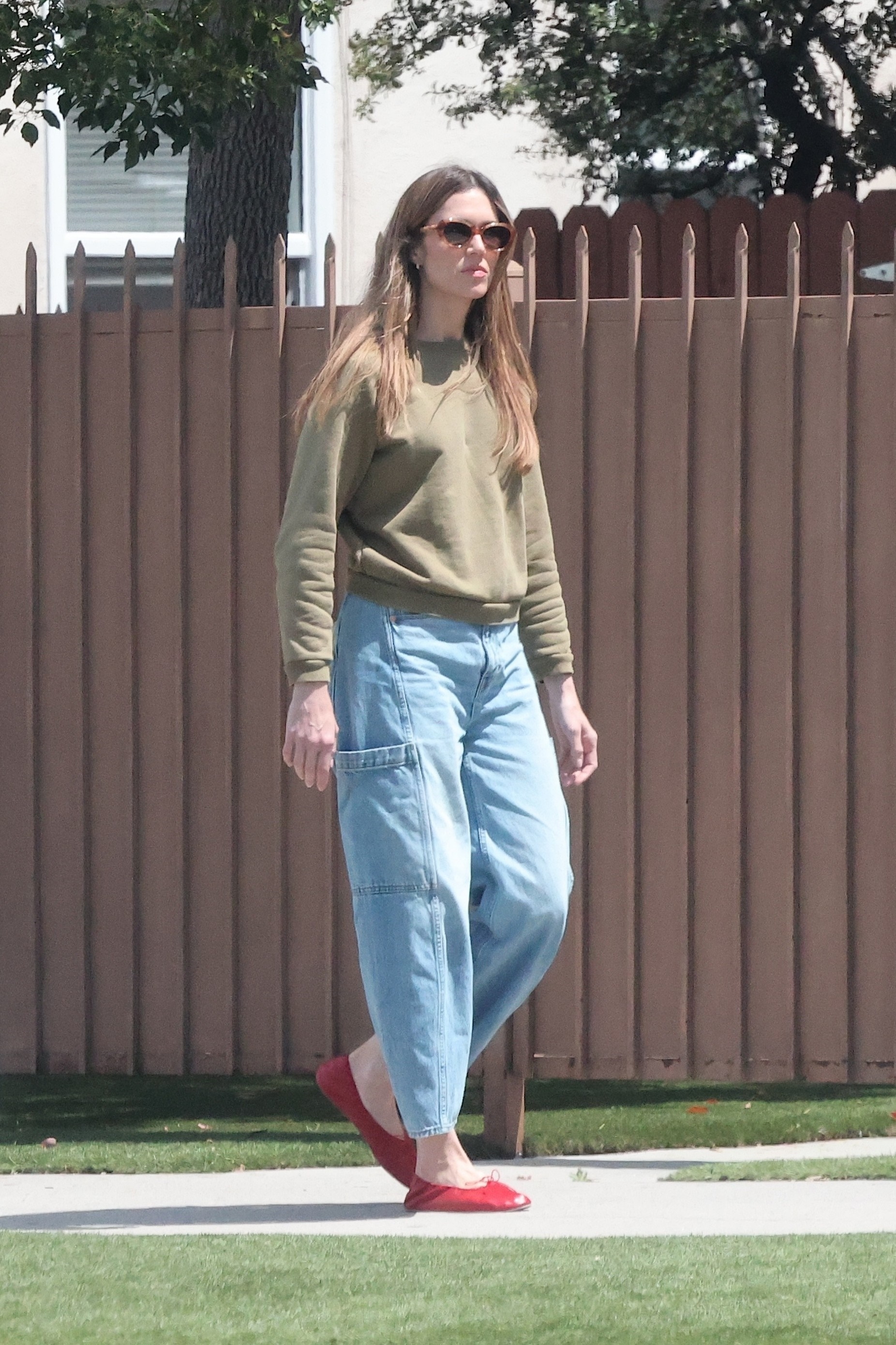 Mandy wears a green sweater, jeans, and red ballet flats.