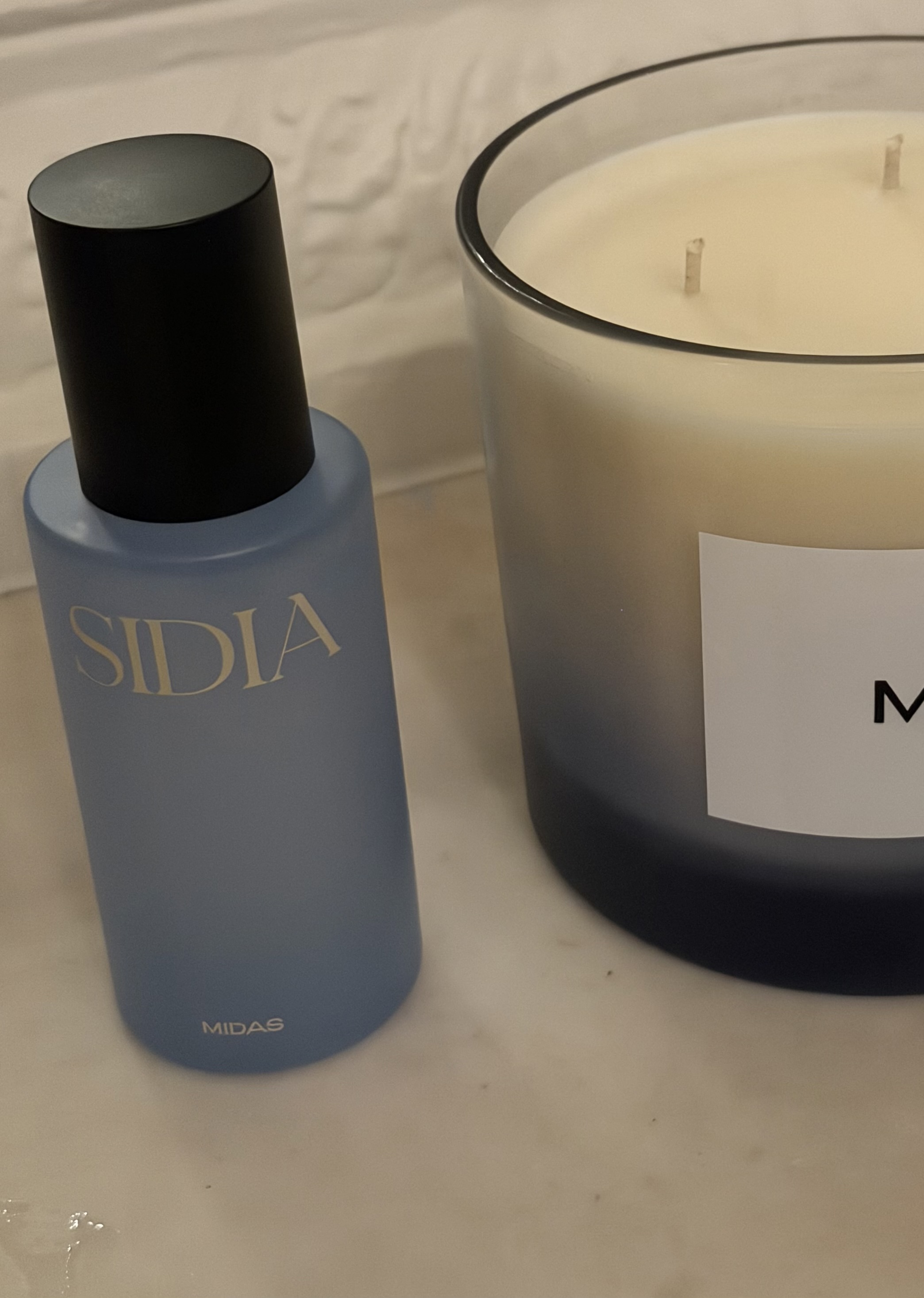 blue bottle of sidia body mist next to a candle