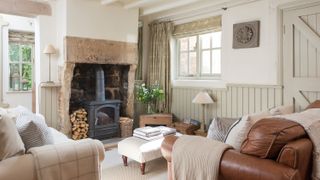 A cream sofa and tan leather sofa in cottage living room with fireplace