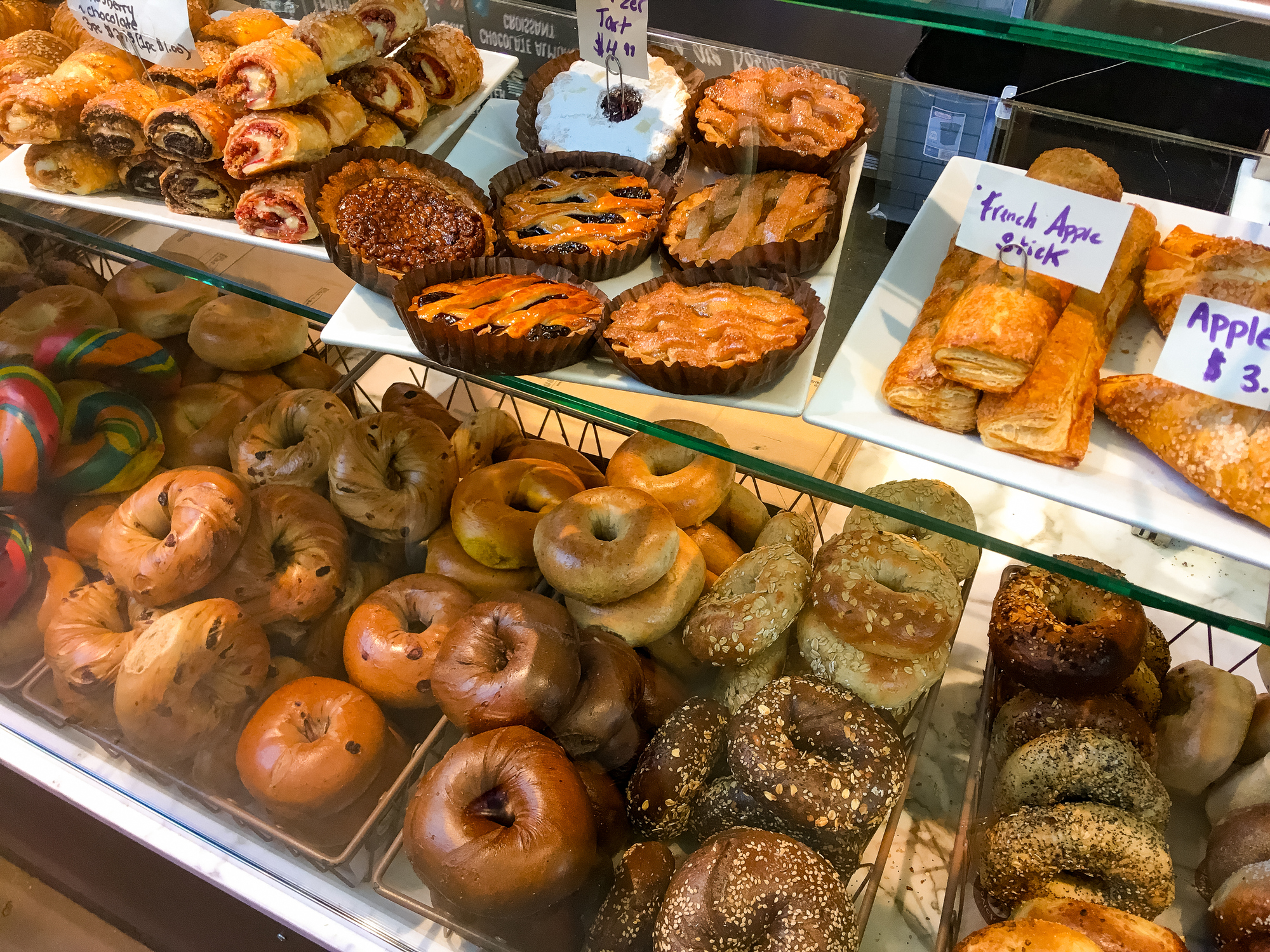 A varied assortment of New York City bakery items and their prices, including different types of bagels.