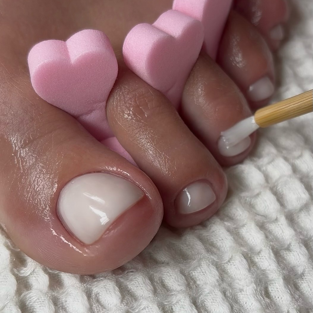 A close up of a milky white pedicure