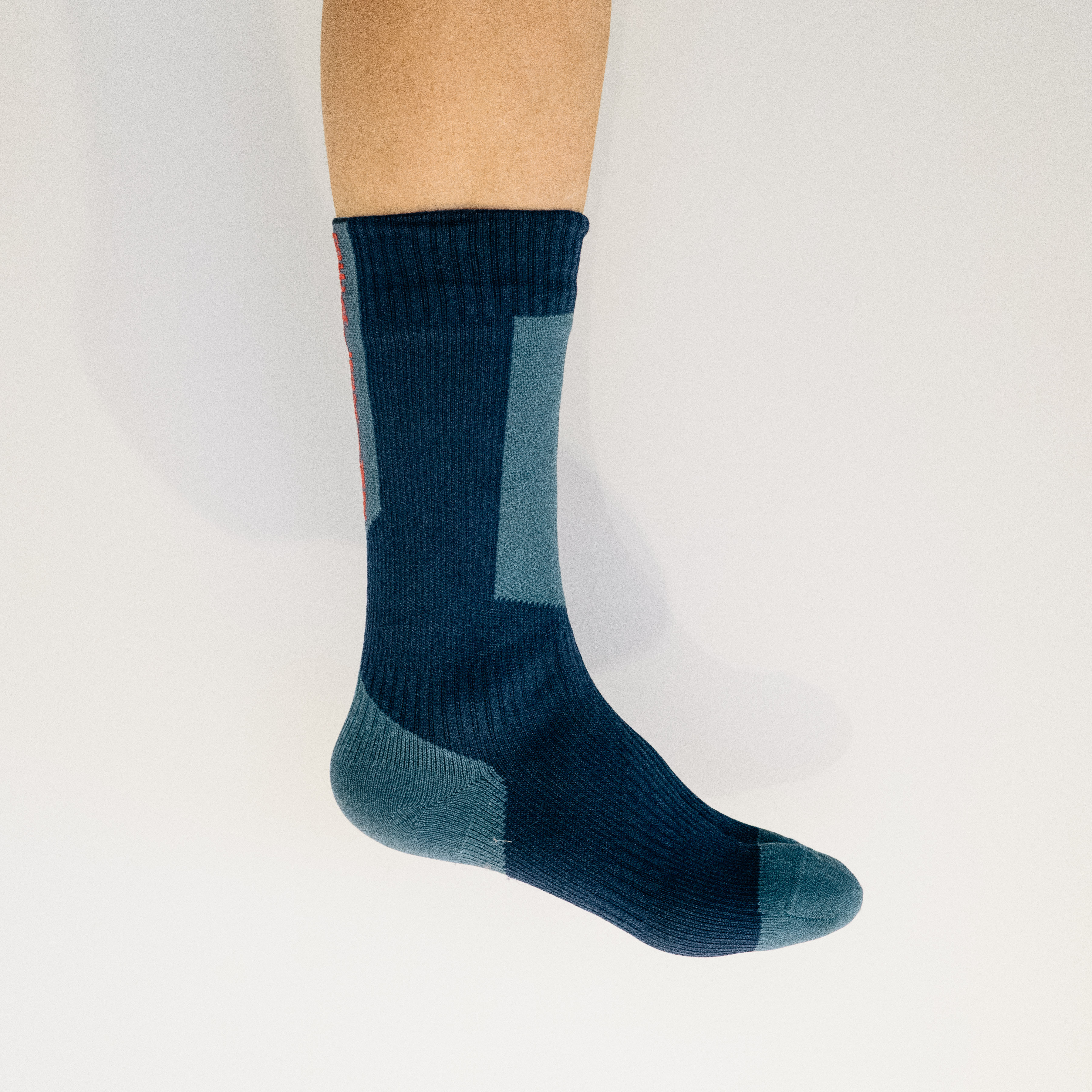 A white leg wears a blue cycling sock against a white background