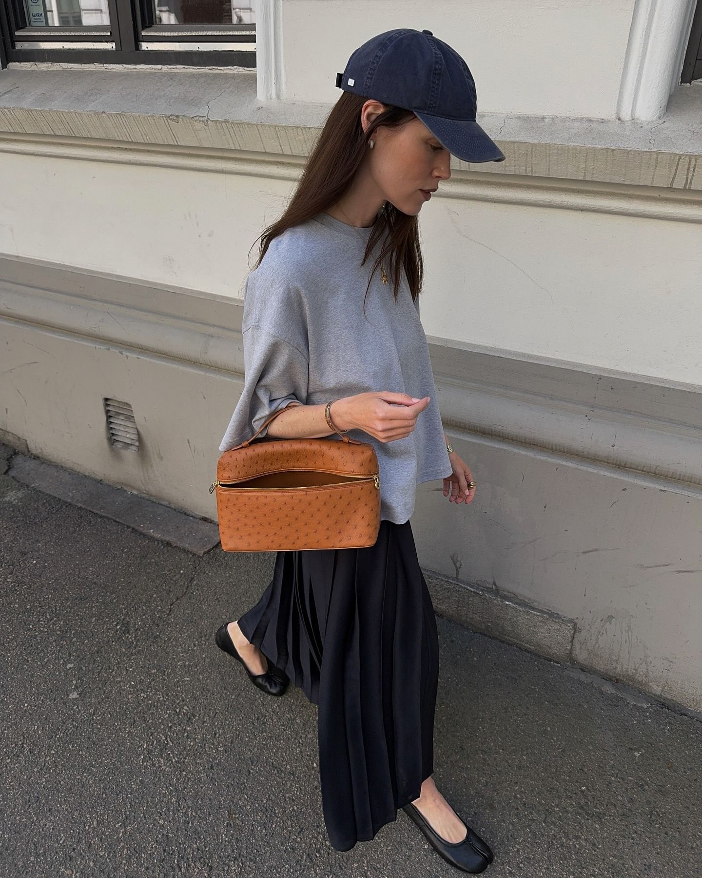 European influencer wearing a grey T-shirt, black midi skirt, and black ballet flats