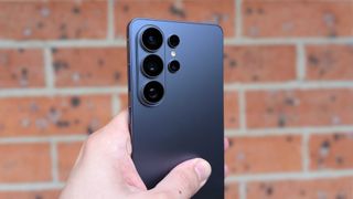 Rear view of the Samsung Galaxy S26 Ultra held up against a brick wall