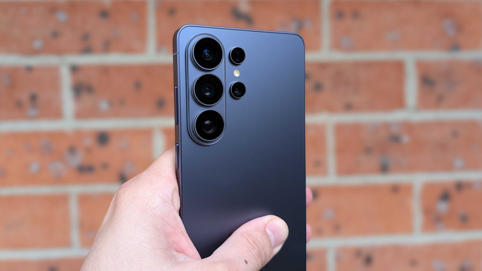 Rear view of the Samsung Galaxy S26 Ultra held up against a brick wall