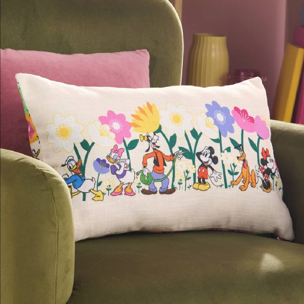 A deep olive green armchair with a cream cushion with various Disney characters on from the Disney Store.