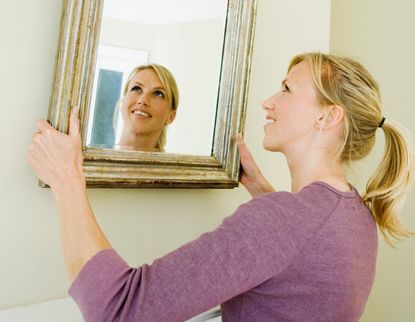 woman hanging a mirror