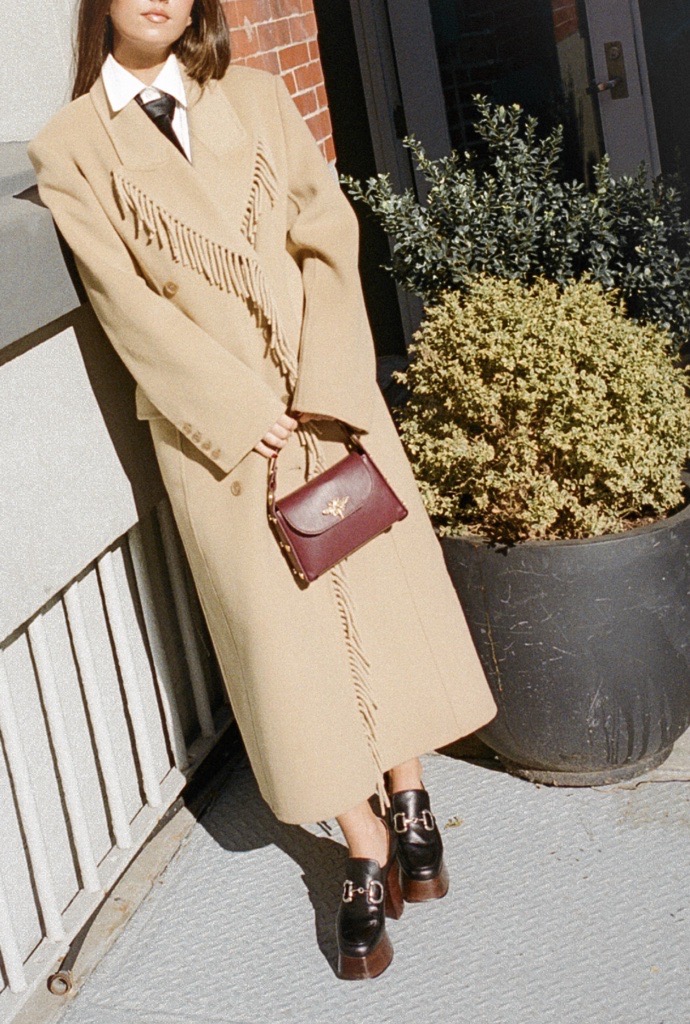 Jessica Habich Thomas wearing a fringe trench coat with a tie at her apartment