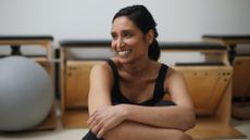 Woman smiling sitting down doing bodyweight Pilates workout