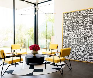 corner with full height window patterned rug monochrome artwork and yellow chairs
