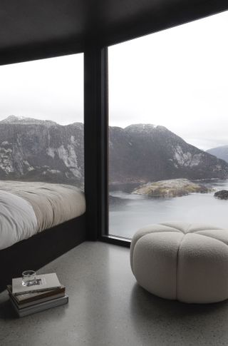 view from inside snøhetta designed cabin, interiors by vipp, view of water and fjord in back ground, valley either side