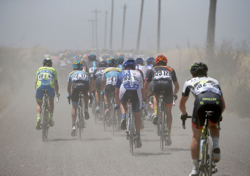 The peloton on a dirt and gravel section of the first stage