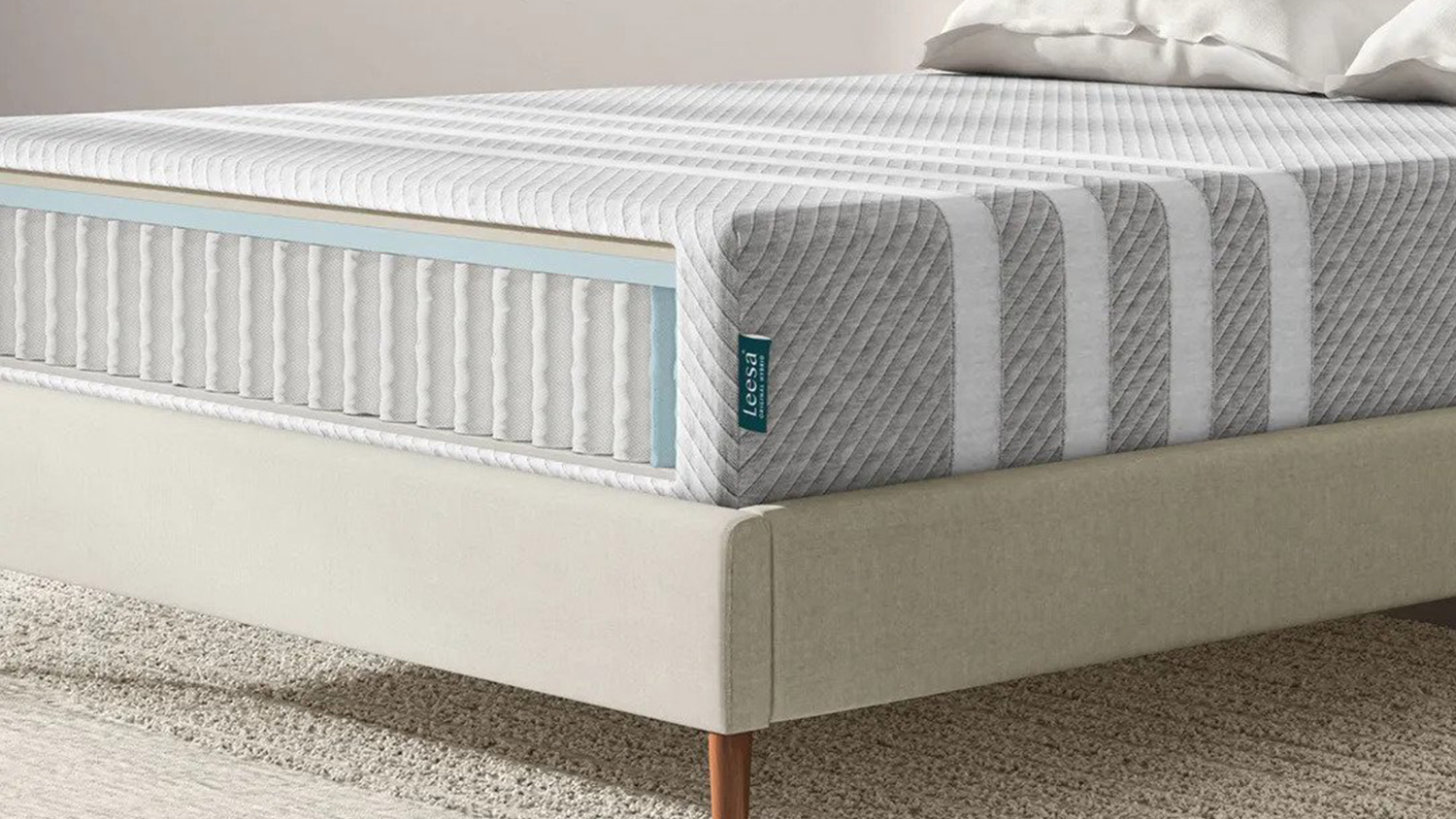 Image shows one corner of the Leesa Original Hybrid Mattress sat on a cream fabric bed frame