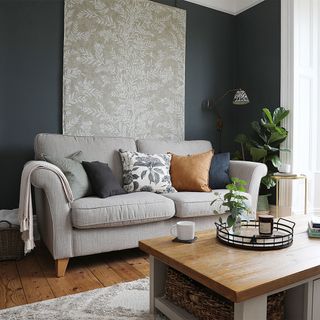 blue living room with grey sofa and wall hanging