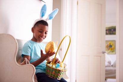 A boy with easter bunny ears holding easter eggs