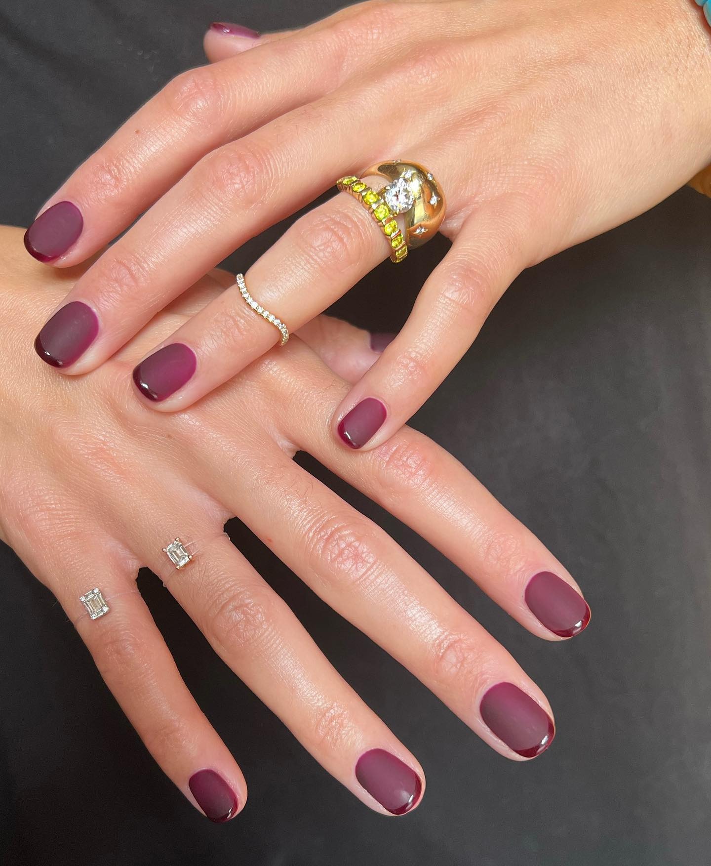 A matte burgundy nail polish design with a glossy burgundy French tip