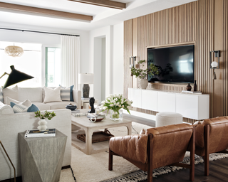 Neutral living room with wooden end table and square white coffee table between couches with tuplips