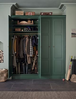 Green entry closet with hanging area, storage above, stone floor and rug