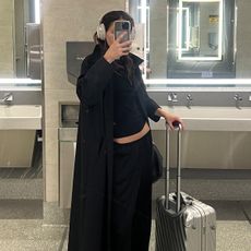 Eliza Huber at LGA Airport with her TUMI international carry-on suitcase.