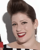 a white woman with light brown hair and red lipstick smiling at the camera
