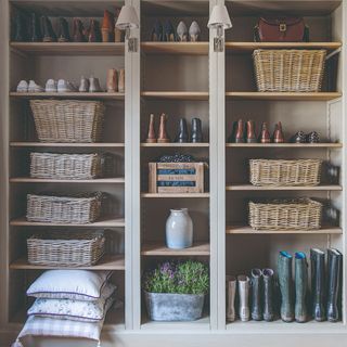 Bookcases turned into customised hallway storage with shoes, cushions and wicker baskets on the shelves