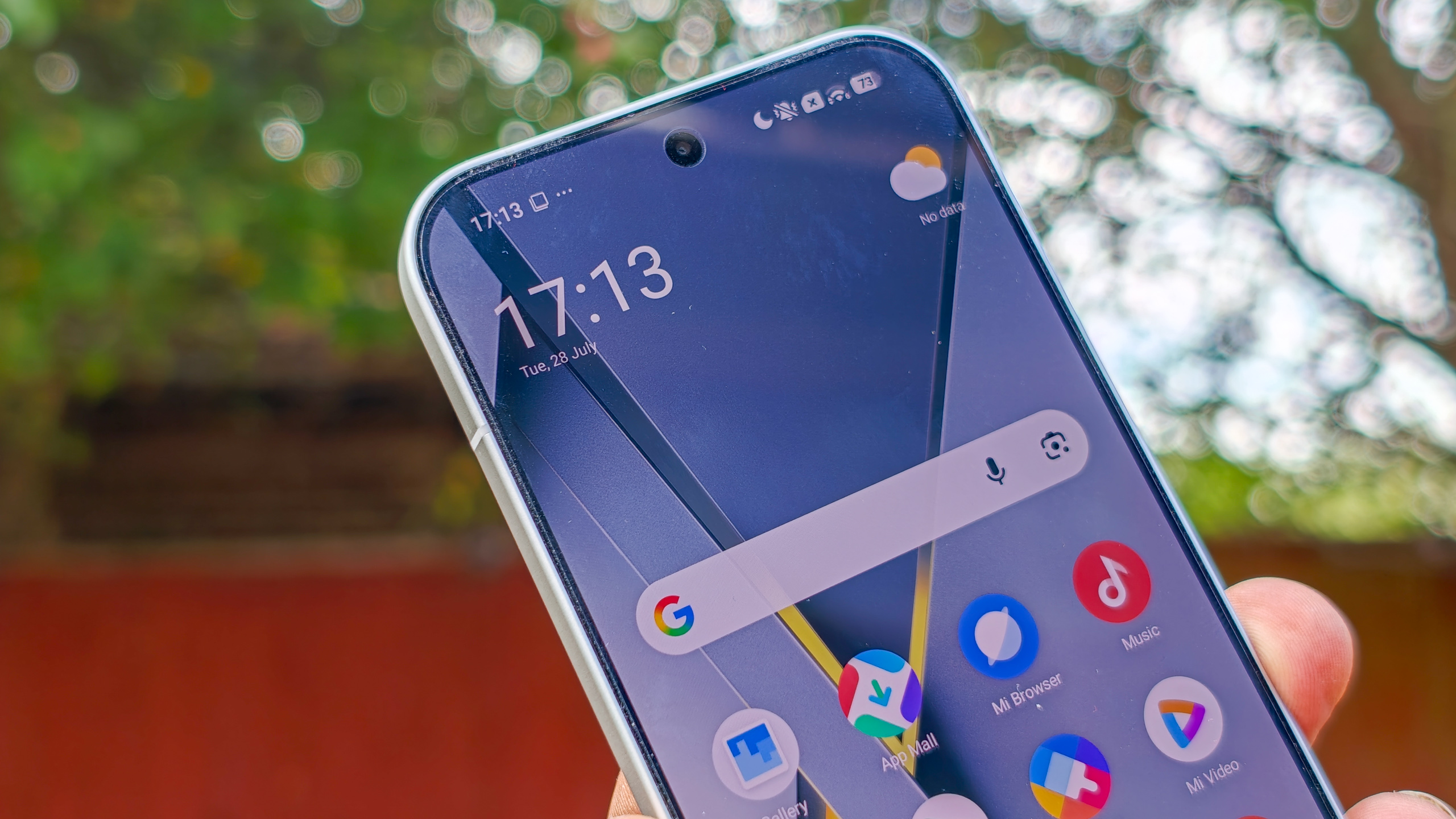 The Poco F8 Pro in Silver in the hand against a garden backdrop