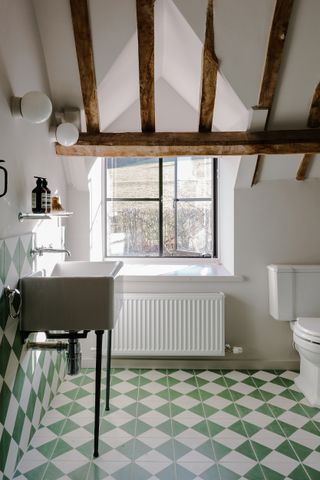 A green and white bathroom with green and white floor and wall tiles in a country cottage style