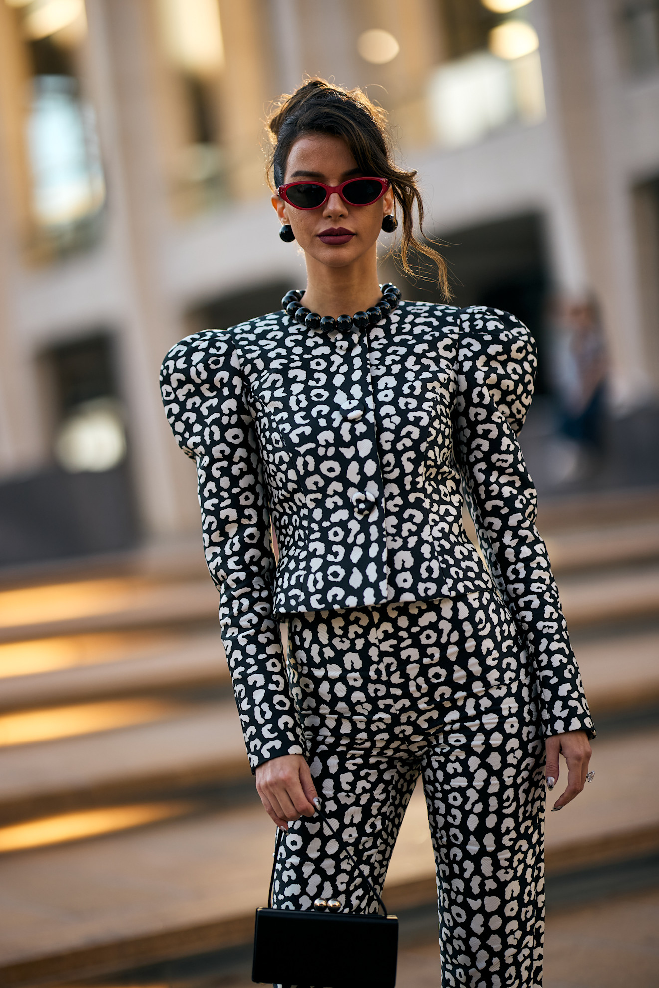 a woman in a black and white suit with red sunglases and brown hair