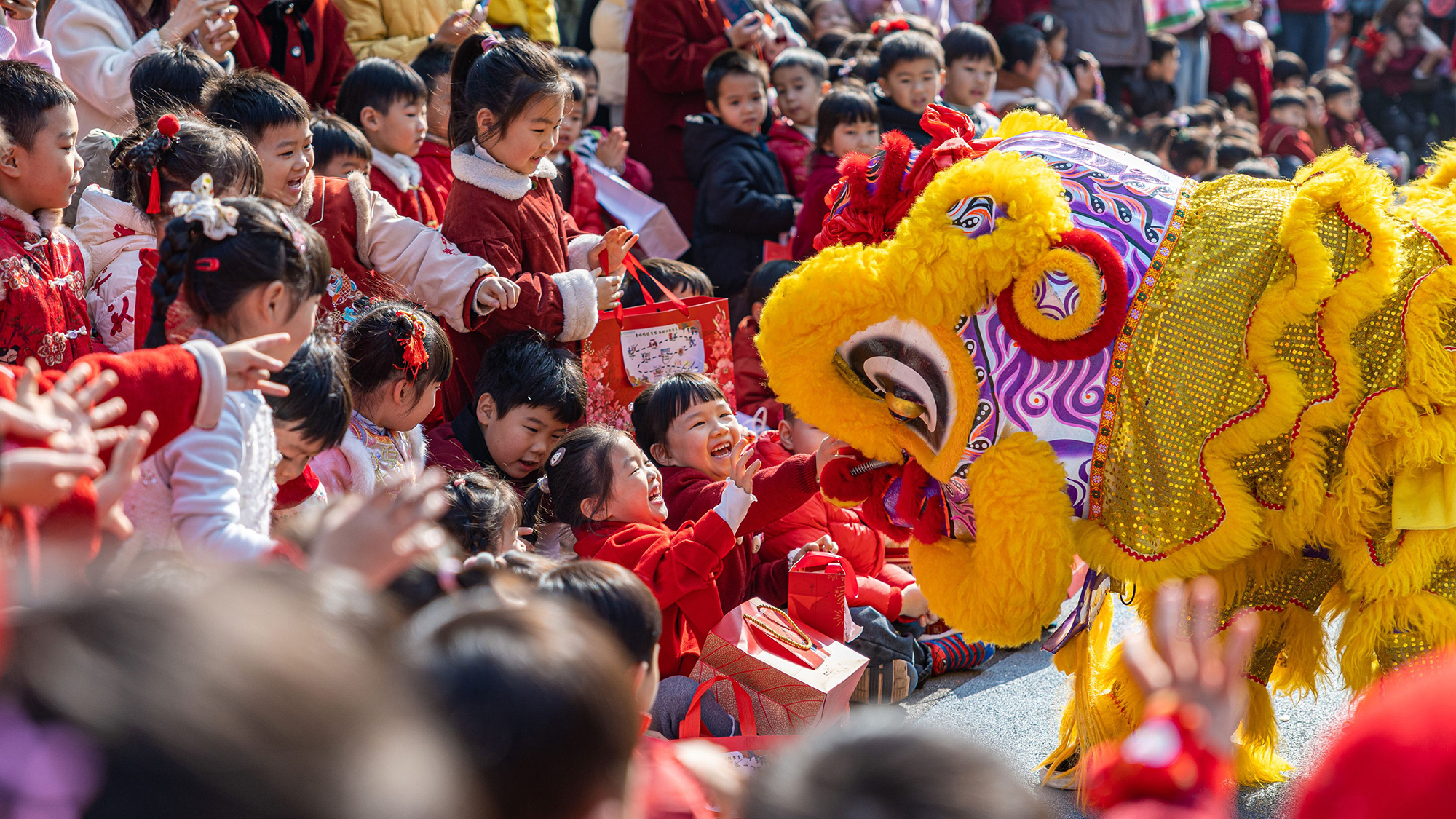 Children interact with a lion dancer at a kindergarten in Wenling City, China