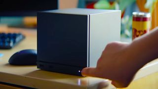 Hand pressing Steam Machine power button on desk.