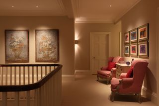 Landing with two armchairs with chest of drawers between and groups of wall art with neutral decor