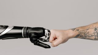 Robot hand fist bumps human hand to symbolise marketing automation