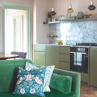 Green single wall kitchen with marble backsplash and green sofa