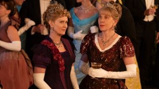 Cynthia Nixon and Christine Baranski stand in conversation at a party in The Gilded Age S3.
