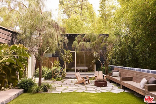 A backyard with two Adirondack chairs, a small lawn, and a wooden bench