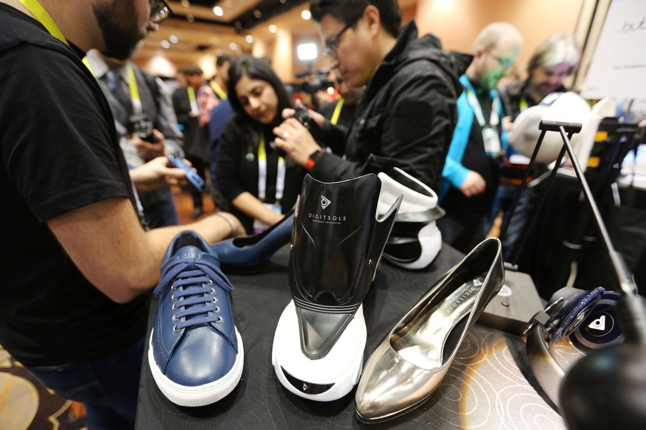 People look at Digisole smart shoes which are controlled by a smartphone app for various actions such as automatic shoe tightening, foot warming, shock absorption measuring and calories burne