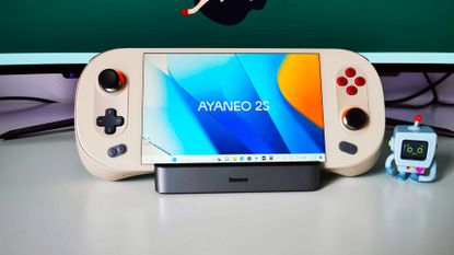Ayaneo 2S on docking station with branded blue and orange desktop wallpaper on white desk