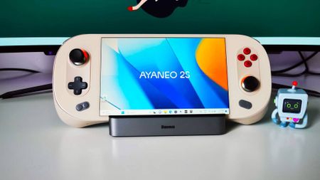Ayaneo 2S on docking station with branded blue and orange desktop wallpaper on white desk
