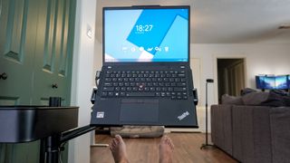 A person working at a DIY rollable workstation on a laptop with their feet up