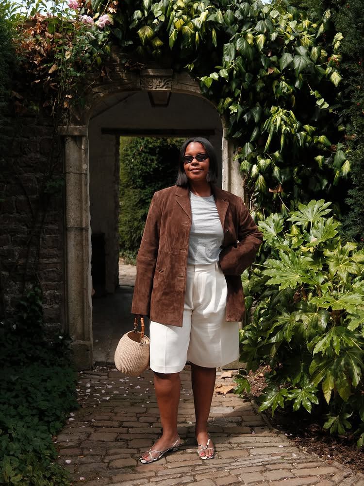 @styleidealist wears a tan suede jacket with cream Bermuda shorts and silver sandals
