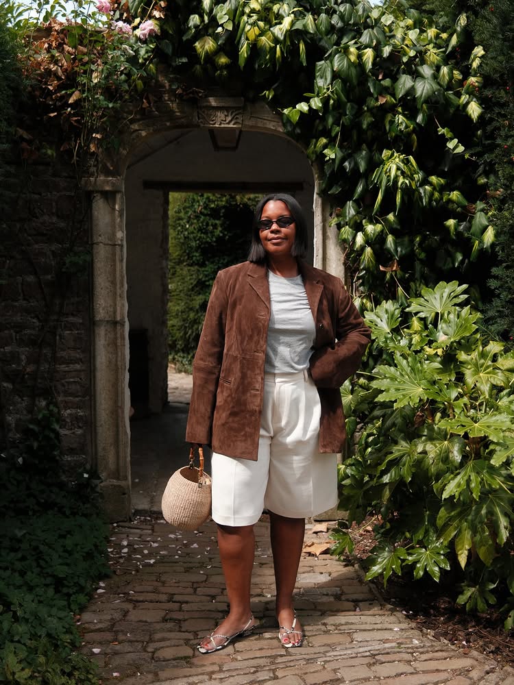 @styleidealist wears a tan suede jacket with cream Bermuda shorts and silver sandals