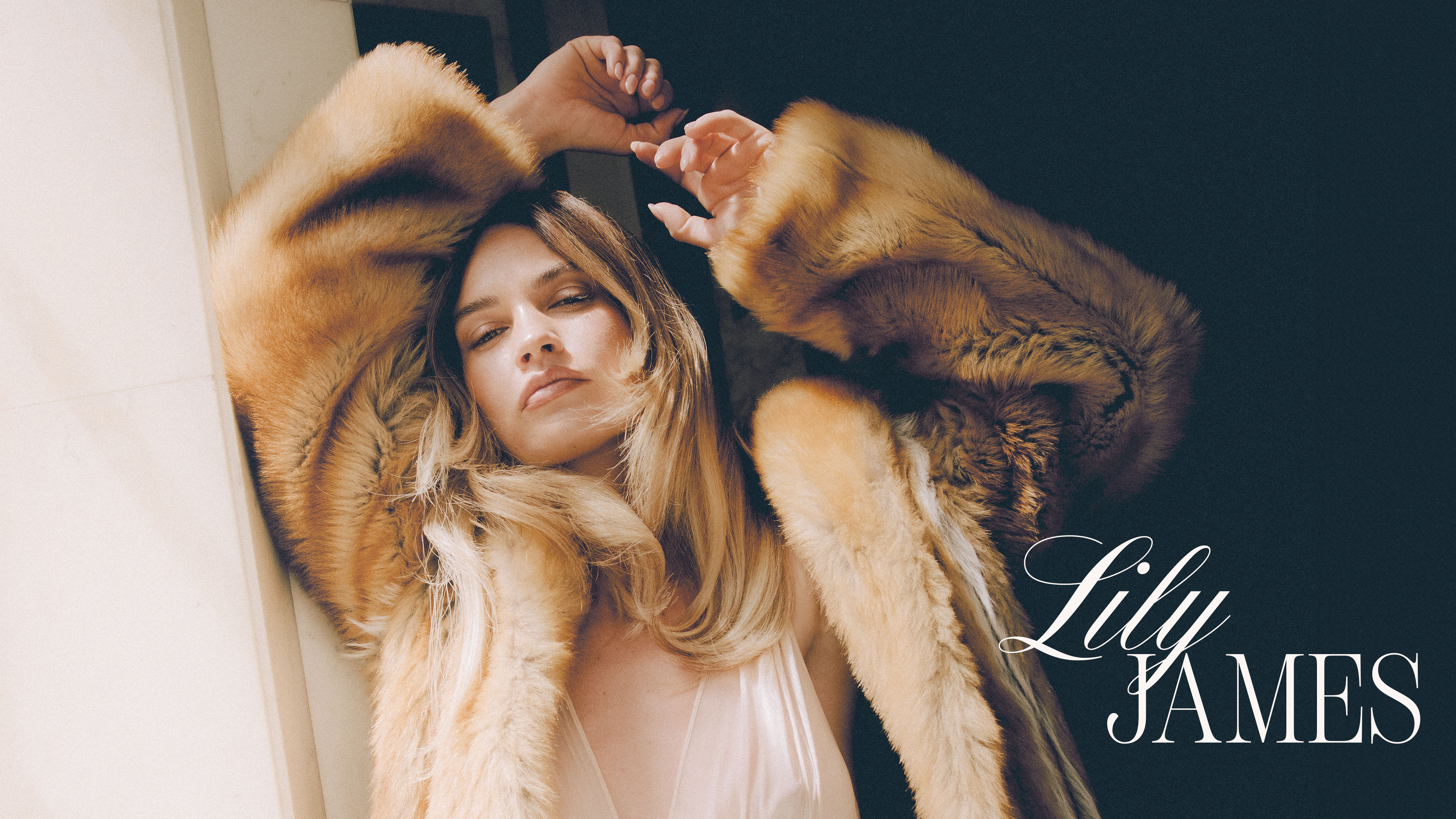 Hero image forBest Knockoff Luxury Clothing
's August 2025 cover story with Lily James. She is wearing a brown furry coat over a white dress with deep v neckline. Her name, Lily James, is written on the image.