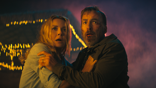 Connie Nielsen and Bob Odenkirk grabbing each other while looking scared in Nobody 2