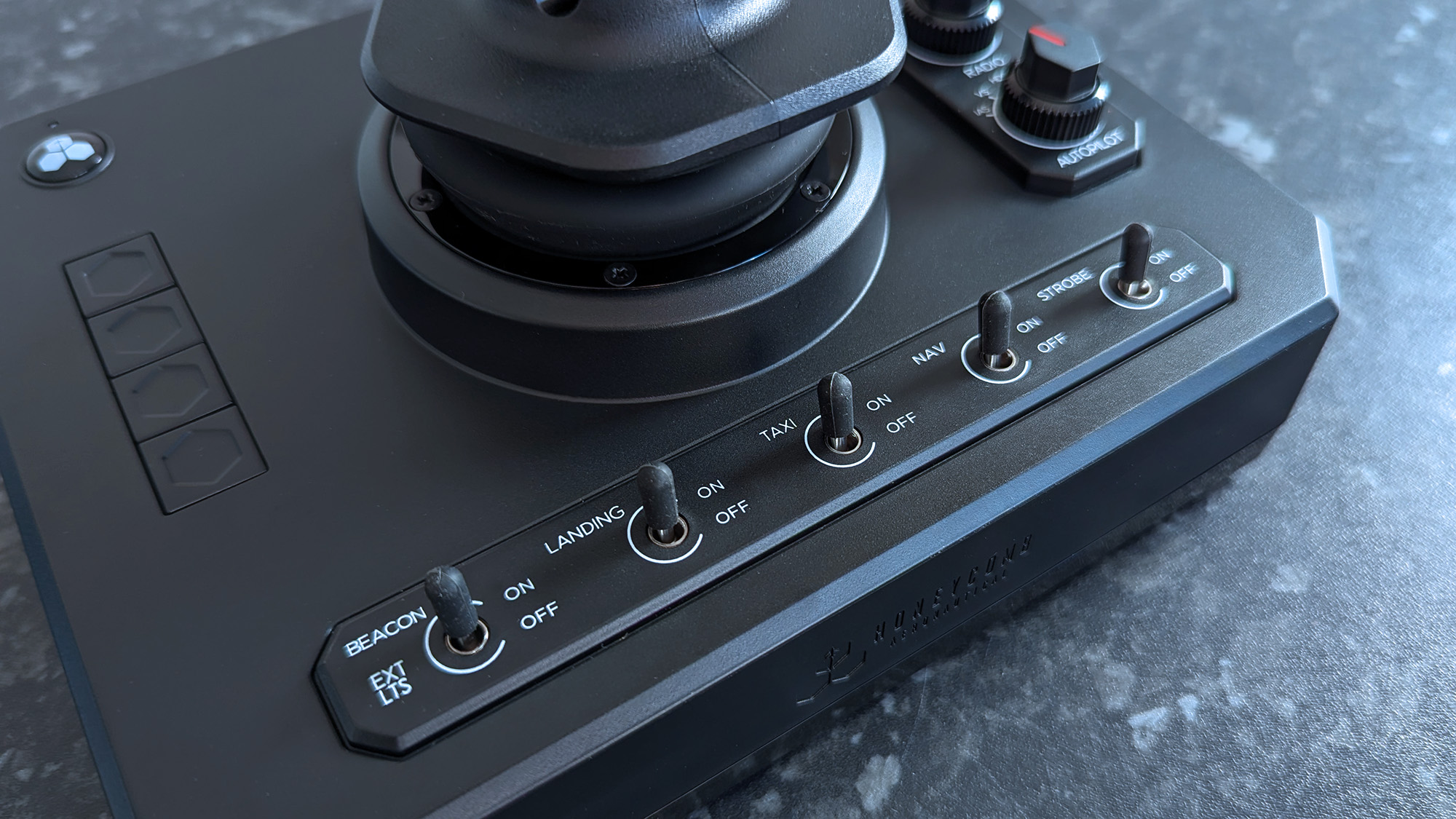 Close-up shot of switches on a Honeycomb Aeronautical Foxtrot Aviation Stick, placed on a marble-patterned countertop