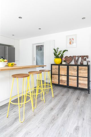 Modern white kitchen with island unit and yellow bar stools