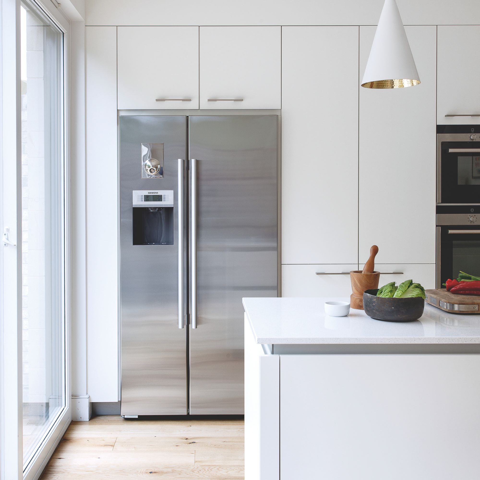 White kitchen with white cabinets and a silver fridge-freezer