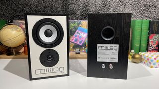 Mission 750 stereo speakers in front of busy shelf with one speaker rear-facing