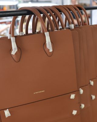 a rack of strathberry bags on a hanger in the ubrique spain workshop where strathberry bags are made